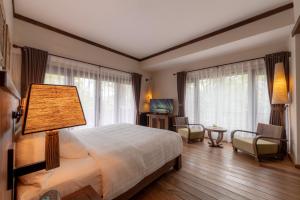 a bedroom with a bed with a lamp and chairs at Melia Ba Vi Mountain Retreat in Hanoi