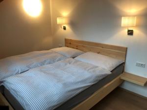 1 cama en un dormitorio con 2 lámparas en la pared en Haus Ramsauer, en Werfenweng