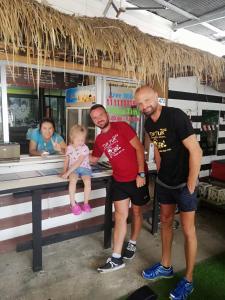 two men and a baby sitting on a bench at Tuk Tuk Guesthouse in Ko Chang