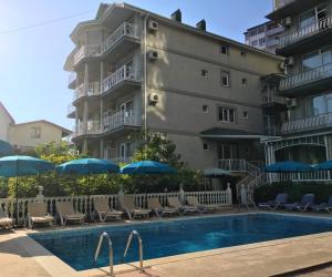 ein Gebäude mit Stühlen und Sonnenschirmen neben einem Pool in der Unterkunft Hotel Odeon in Adler