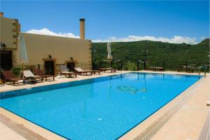 una gran piscina azul con sillas y montañas en el fondo en Maria Villas en Kíssamos