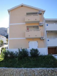 un bâtiment avec une clôture blanche devant lui dans l'établissement Apartments Mikulan Nara, à Baška