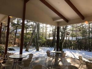 a patio with tables and chairs and a large window at Hotel Karuizawa Elegance in Karuizawa