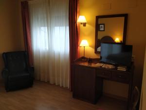 a hotel room with a television and a desk with a chair at Hotel Sierra de Andujar in Virgen de la Cabeza