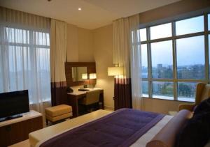 a hotel room with a bed and a desk and window at The Envoy Hotel Abuja in Abuja