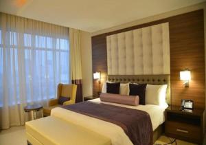 a hotel room with a large bed and a window at The Envoy Hotel Abuja in Abuja