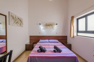 ein Schlafzimmer mit einem Bett mit violetter Bettwäsche und einem Fenster in der Unterkunft Blue Harbour 2 bedroom Seafront Apartments with stunning seaviews - by Getawaysmalta in St Paul's Bay