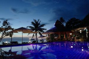 a swimming pool with umbrellas and the ocean at night at Nature Beach Resort in Ko Chang