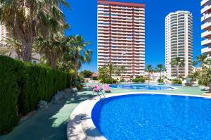 una piscina con palmeras y edificios altos en Villas Guzman - Apartamento Coral Beach, en Calpe