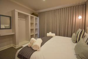 1 dormitorio con 1 cama blanca grande y toallas. en Willow Rest Villas en Clarens