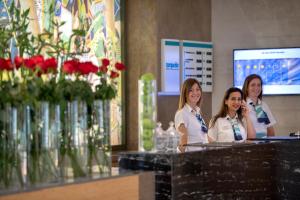 Tres mujeres están detrás de un mostrador con flores. en Turquoise Hotel, en Side
