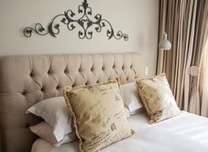 a bedroom with a bed with a large headboard and pillows at Avemore Lagratitude No 6 - with backup power for loadshedding in Stellenbosch