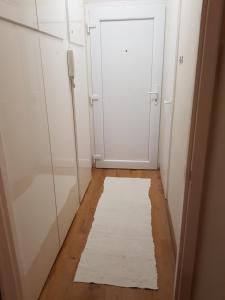 un pasillo con una puerta blanca y una alfombra blanca en Lia Apartman en Nyíregyháza