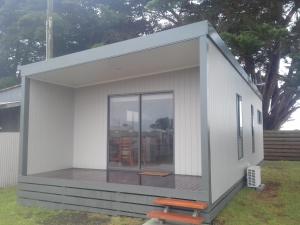 a small white house with a deck at Gum Tree Caravan Park in Port Fairy