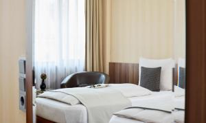 una habitación de hotel con dos camas y una silla en Living Hotel Düsseldorf, en Düsseldorf
