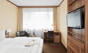 Habitación de hotel con cama y TV de pantalla plana. en Living Hotel Düsseldorf, en Düsseldorf