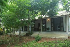 a house with a porch and trees in front of it at Villa Greenary in Unawatuna