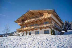 um grande edifício de madeira no topo de uma encosta coberta de neve em Chalet Apartment Obermanzl em Hopfgarten im Brixental