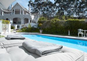 a pool with two lounge chairs next to a house at Parkes Manor in Knysna