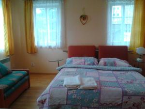 ein Schlafzimmer mit einem Bett, einem Sofa und Fenstern in der Unterkunft Jiřetínská chaloupka in Jiřetín pod Jedlovou