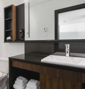 a bathroom with a sink and a mirror and towels at Littoral - Hôtel & Spa in Quebec City