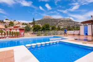 mężczyzna stojący obok basenu z górą w obiekcie Villas Guzman - Dora w mieście Calpe