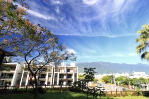 a white building with mountains in the background at 去那邊民宿-花蓮市電梯民宿 in Hualien City
