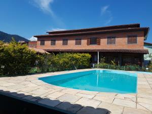 uma piscina em frente a uma casa em Sol e Cia casa de temporada em Caraguatatuba
