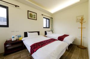 花蓮市にある9x9 Homestayのベッド2台が備わる客室で、壁にクロスが付いています。