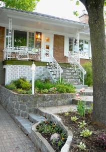 una casa con porche blanco y escaleras delante en B&B La Bedondaine, en Quebec