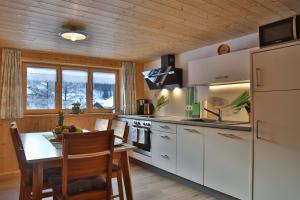 una cocina con armarios blancos y una mesa con sillas. en Apartments Hänsler, en Mellau