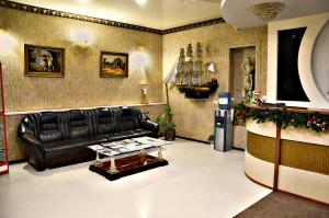 uma sala de estar com um sofá de couro preto e uma mesa em Hotel Astoria em Volgogrado
