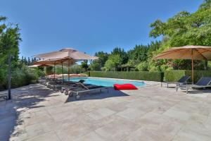 a swimming pool with umbrellas and lounge chairs at Les Carmes and spa in Le Thor