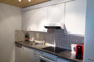 a kitchen with white cabinets and a sink at Haus zur Tanne - CharmingStay in Flumserberg