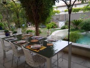 uma mesa num quintal com cadeiras e uma piscina em Le Patio Des Senteurs em Verzeille