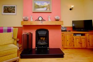 een woonkamer met een open haard en een televisie bij Cottage 108 - Cleggan in Cleggan