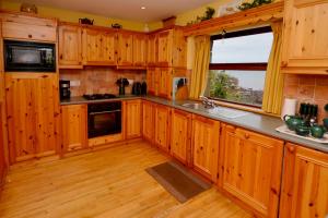 a kitchen with wooden cabinets and a large window at Cottage 108 - Cleggan in Cleggan