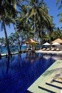 una piscina con palmeras y un complejo en Spa Village Resort Tembok Bali - Small Luxury Hotels of the World, en Tejakula