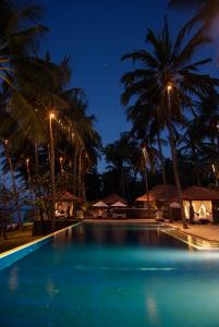 una piscina con palmeras por la noche en Spa Village Resort Tembok Bali - Small Luxury Hotels of the World, en Tejakula