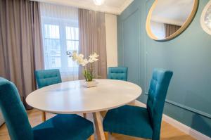 a dining room with a white table and blue chairs at Grand Apartments - Willa Sobieski in Sopot