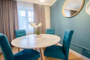 ソポトにあるGrand Apartments - Willa Sobieskiのダイニングルーム(白いテーブル、青い椅子付)