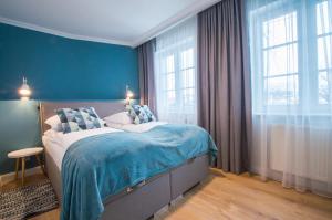 a bedroom with a bed with blue walls and windows at Grand Apartments - Willa Sobieski in Sopot