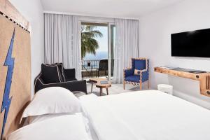 a hotel room with a bed and a television at Myconian Imperial - Leading Hotels of the World in Elia Beach