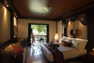 a bedroom with a bed and a woman standing outside a window at Spa Village Resort Tembok Bali - Small Luxury Hotels of the World in Tejakula