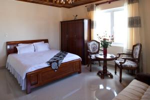 a bedroom with a bed and a couch and a window at Villa Du Lac Da Lat in Da Lat