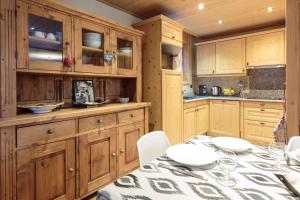 a kitchen with wooden cabinets and a table with chairs at Chamois Apartment- Chamonix All Year in Chamonix