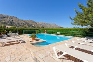 a swimming pool with two lounge chairs and a table at Can Venzala in Pollença