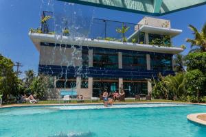 a swimming pool with a fountain in front of a building at Pousada Stand Up! Guarujá in Guarujá