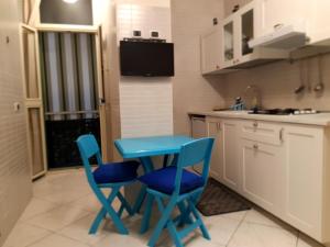 - une cuisine avec deux chaises bleues et une table dans l'établissement Metropolis Stazione Centrale, à Naples