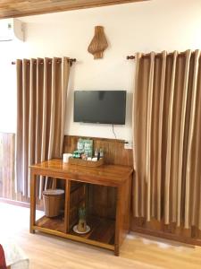 uma sala de estar com uma televisão e uma mesa de madeira em Orchard Fruit Farm Bungalow em Phu Quoc